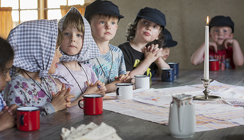 Barn står runt ett bord och väntar på fika.