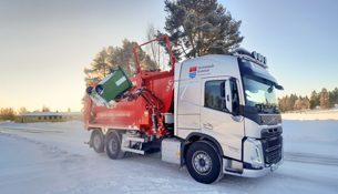 En röd och vit lastbil som kör på en snötäckt väg.