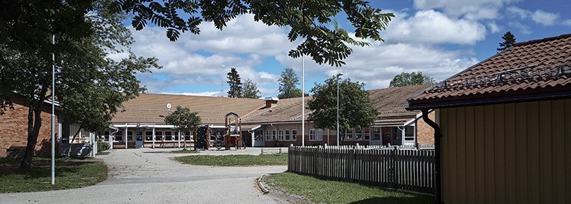 Låg byggnad i sommarmiljö.
