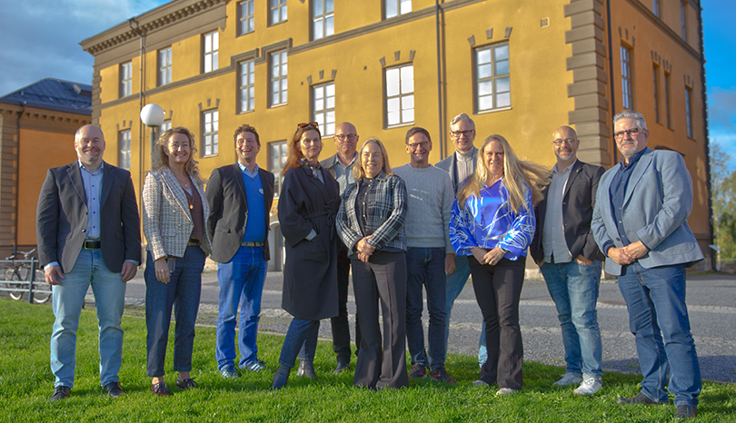 En grupp människor. I bakgrunden en gul tegelbyggnad.