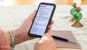 Hand håller i telefon som visar digitalt röstkort.
