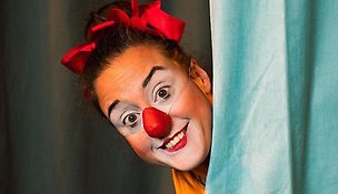 Clown tittar fram bakom en gardin.